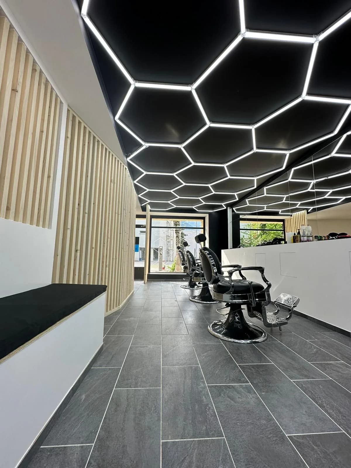 Intérieur du salon RS Concept à Sierre, plafond hexagonal LED et fauteuils barbier